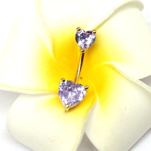 Piercing nombril cœur doré avec zircons violets sur des pétales de Frangipanier