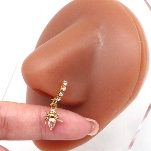 Macro shot of gold spider nose ring with sparkling zircons on a silicone display