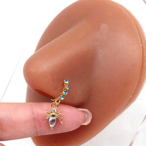 Macro shot of a gold spider nose ring with blue crystal pendant on silicone model