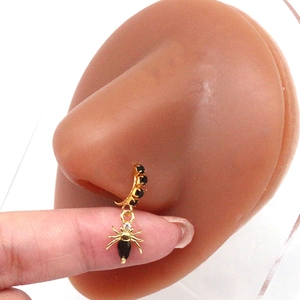 Gothic gold nose ring with black gemstones and a detailed spider pendant macro view