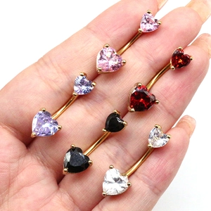 Détail de piercings de nombril en forme de cœur avec zircons colorés posés sur la main