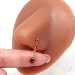 Macro shot of gold septum ring with red zircon stones and spider pendant on model
