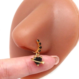 Close-up of heart-shaped Saturn planet nose ring with black stones in gold finish