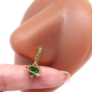 Detail of a heart-shaped green gemstone nose ring with Saturn design in gold plating