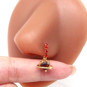 Detail view of gold nose stud with red heart stone and planetary ring on silicone model