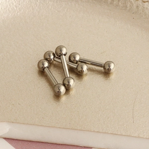 Macro view of G23 titanium barbell piercing studs with silver metallic finish on a display