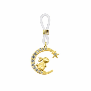 Détail d'un pendentif lune et lapin doré avec pierres claires et boucle en silicone blanc