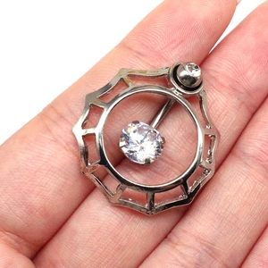 Macro detail of silver spiderweb belly ring with round zircon held by a hand