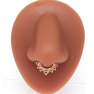 Detailed view of a golden vintage fan-shaped septum ring on a realistic silicone nose model