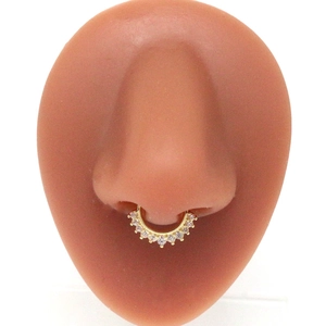 Detail view of a gold-plated nose ring with pink zircons on a silicone model