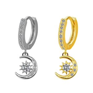 Dettaglio di orecchini celesti in oro e argento con motivi di luna e sole in zirconi