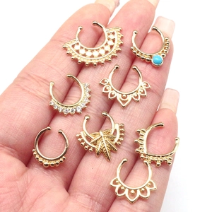 Detailed view of eight golden faux nose rings and ear cuffs held in palm for scale