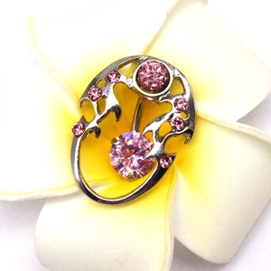 Macro shot of stainless steel navel ring featuring pink crystals on white flowers