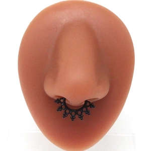 Matte black stainless steel faux septum ring with vintage tribal sun pattern on a nose model