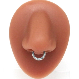 Macro shot of silver septum ring with blue zircon inlay on silicone nose model