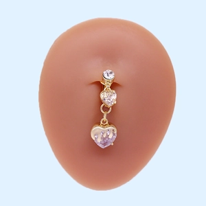 Detail eines goldenen Herz-Bauchnabelpiercings mit Kristallen auf einem Silikonmodell