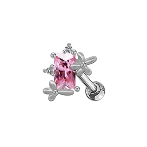 Détail d'une boucle d'oreille argentée avec une pierre rose rectangulaire et fleurs