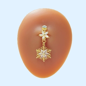 Goldener Bauchnabelpiercing mit Schneeflocken-Anhängern und Zirkon-Kristallen auf Silikonmodell