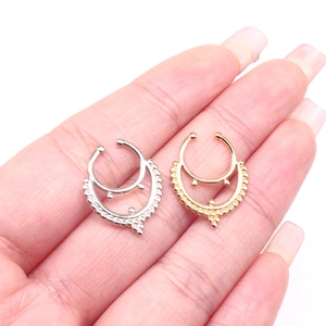 Detail of gold and silver U-shaped septum nose rings with beaded trim held by fingers
