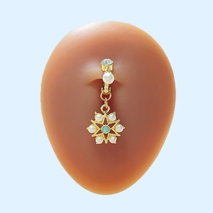 Goldenes Bauchnabelpiercing Schneeflocke mit Perlen und grünem Edelstein am Model
