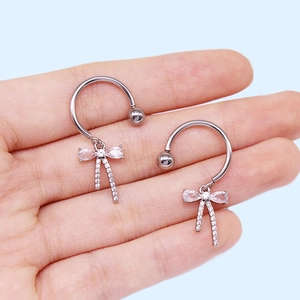 Détail de bijoux de sein avec nœud et zircon rose sur acier inoxydable poli