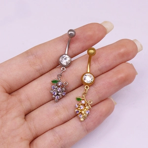 Primer plano de piercings de ombligo con diseño de uva en tonos plata y oro con cristales