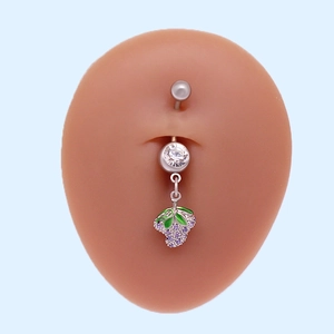 Detalle del piercing de ombligo con colgante de uva morada y hoja de esmalte verde