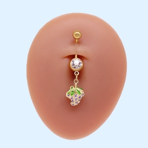 Detalle de un piercing para el ombligo de fresa dorada con circones morados en modelo de silicona