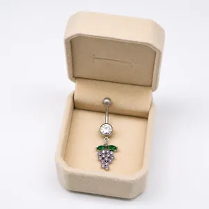 Detalle de piercing de ombligo con diseño de uva con cristales púrpuras y hojas verdes
