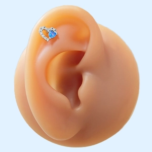 Detailed view of silver heart stud earring with blue opal and zircon on an ear model