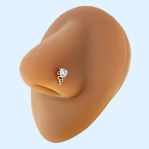 Dettaglio di un piercing al naso a forma di cuore con cristallo e design a freccia
