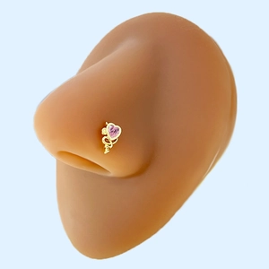 Macro shot of gold-plated heart-shaped nose stud with pink gemstone on silicone model