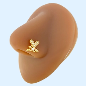 Macro detail of gold-plated heart-shaped nose stud with Love script and tiny pearls