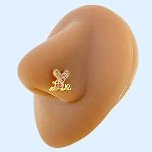 Macro detail of heart-shaped Love nose stud in gold finish with pink rhinestones