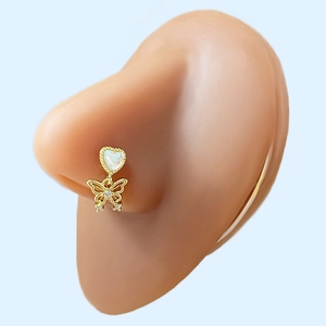 Close-up of gold nose stud with heart opal and hollow butterfly pendant on silicone model