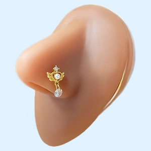 Detail of gold nose stud with heart wing design, white pearl, and dangling zircon stone