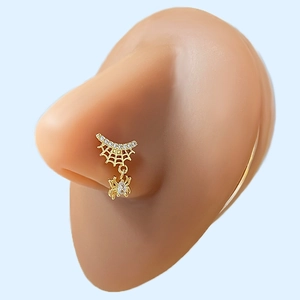 Macro shot of gold spider web nose ring with zircon pendant on a silicone nose model