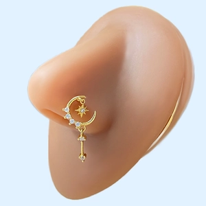 Detail view of a gold star and moon nose ring with sparkling cubic zirconia on a model