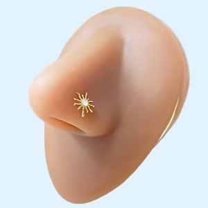 Close-up of gold starburst nose stud with white gemstone on silicone nose model