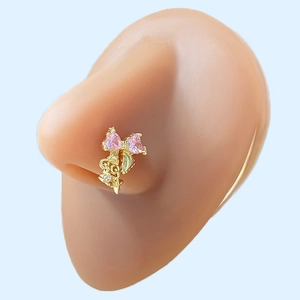 Macro detail of a gold nose stud featuring pink heart-shaped zircons and a star pendant