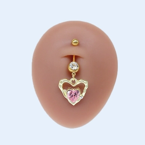 Détail d'un piercing de nombril en forme de cœur doré avec zircon rose sur modèle