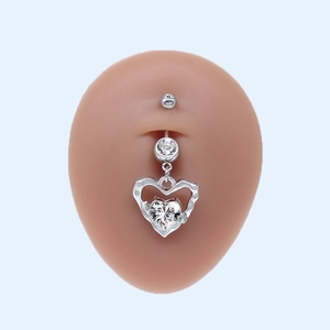 Détail du piercing de nombril avec pendentif cœur en métal argenté et oxyde de zirconium