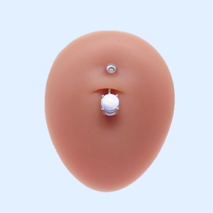 Piercing de nombril argenté avec boule incrustée de paillettes bleues sur modèle