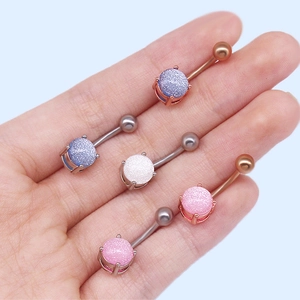 Détail de cinq piercings de nombril avec pierres scintillantes en argent et or rose