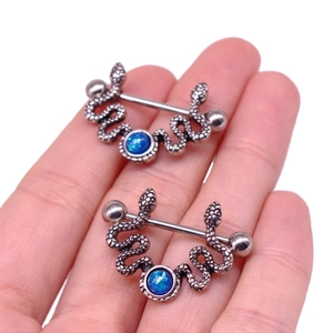 Macro shot of silver snake nipple rings featuring blue opal stones held by hand