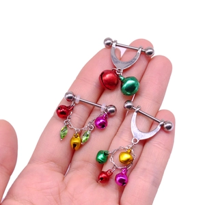 Close-up of colorful Christmas bells and rhinestone leaf nipple rings in hand
