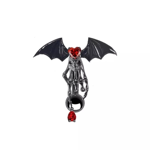 Macro view of gothic bat belly ring with red heart gemstone and black skull hand details