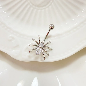 Detailed macro view of punk spider belly ring with sparkling cubic zirconia on a shell plate