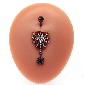 Macro shot of spider web belly ring with heart zircon and dangling spider pendant