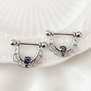 Dettaglio dei piercing per capezzoli in argento con zirconi viola e design a pizzo